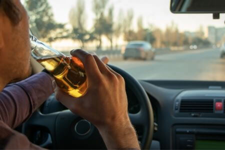 Man driving car drinking a beer