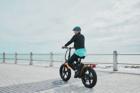 Woman riding e-bike on beach boardwalk