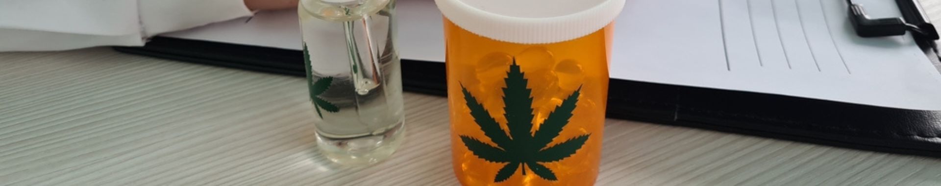 Doctor's desk with pill bottle with weed leaf.